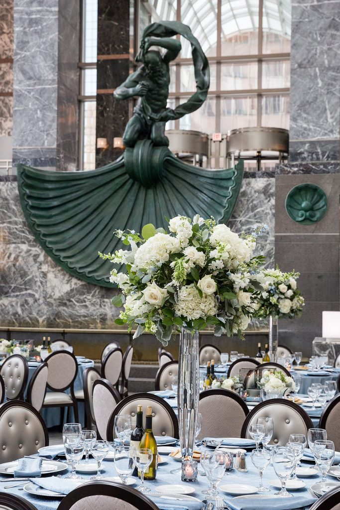 Tall centerpiece at a wedding reception featuring whites and greens.