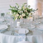 A side profile view of a low floral centerpiece featuring white wedding flowers on a white and light blue tablescape at Company 251. Photo by Tim Tab Studios.