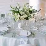 A side profile view of a low floral centerpiece featuring white wedding flowers on a white and light blue tablescape at Company 251. Photo by Tim Tab Studios.